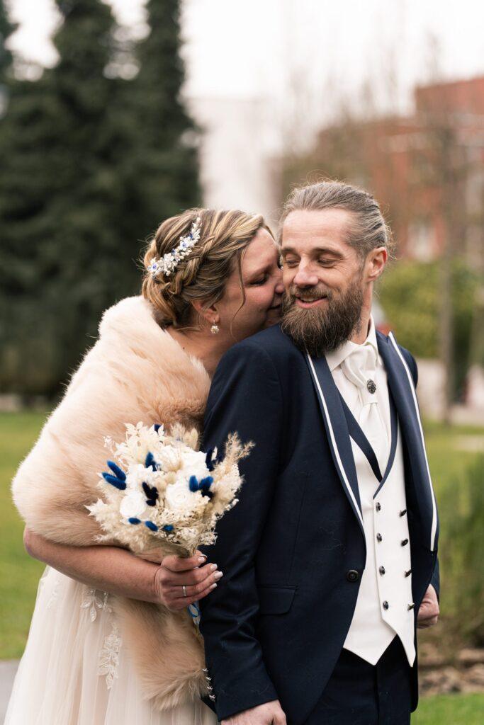 Mariée embrassant le marié en costume bleu, séance photo de mariage hivernal à Lille