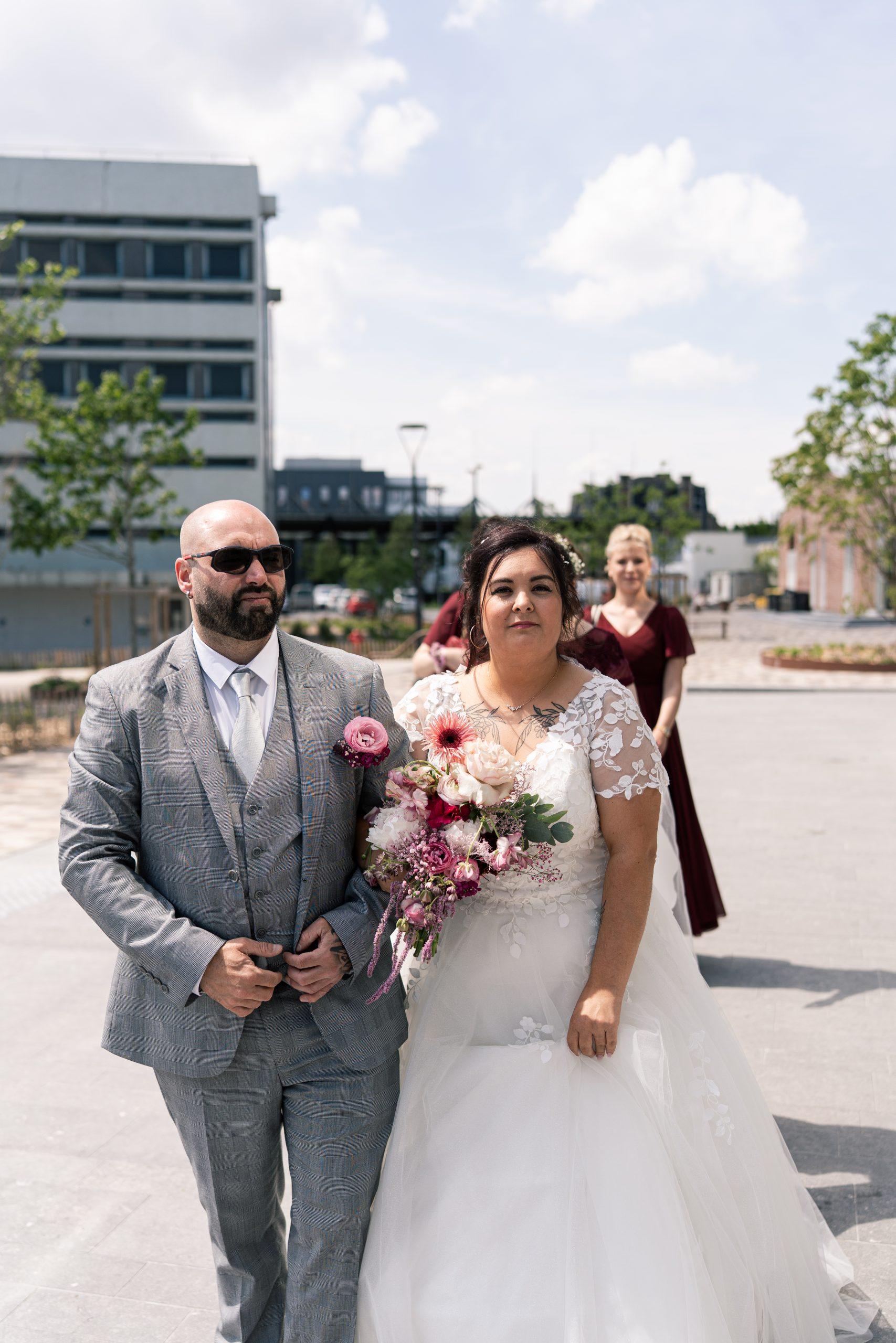 Émilie en robe de mariée et tenant son bouquet lors de son arrivée à la cérémonie civile à Denain
