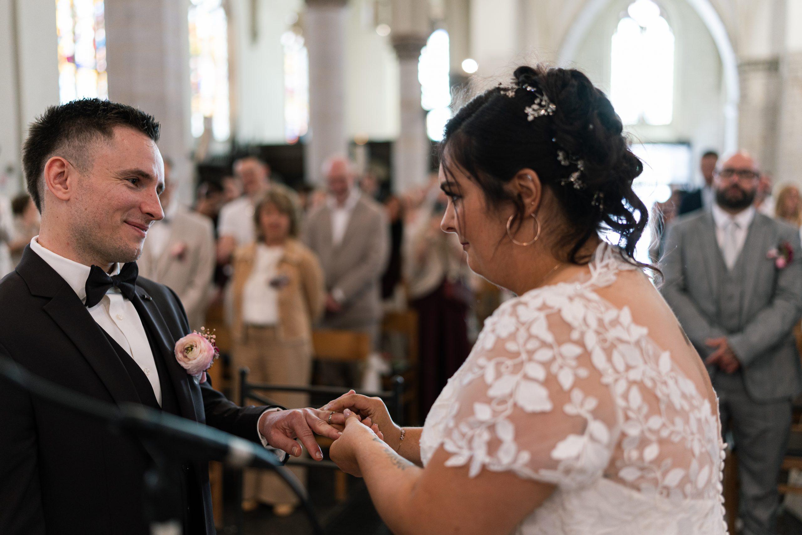 Émilie passe l’alliance au doigt de Théo pendant leur cérémonie de mariage