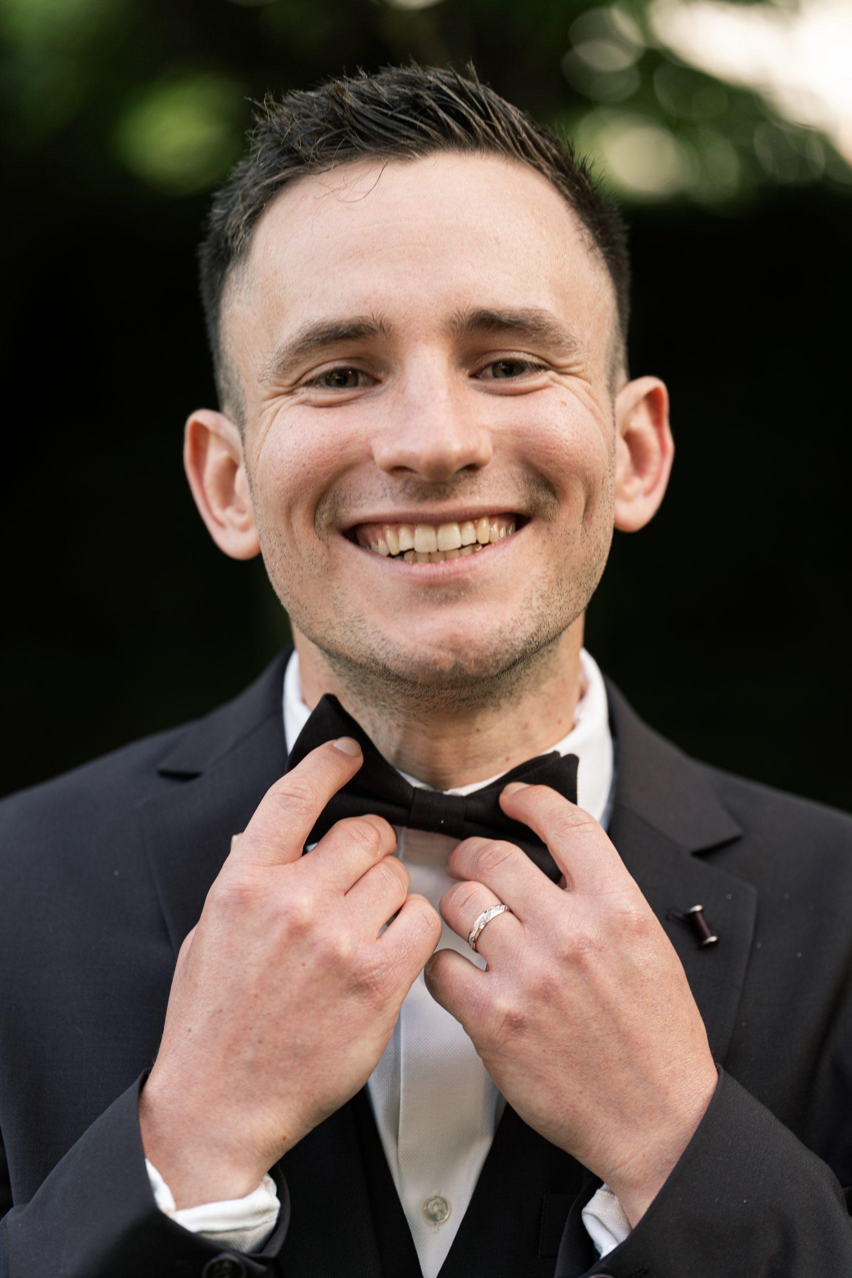 Théo sourit en ajustant son nœud papillon pendant sa séance photo