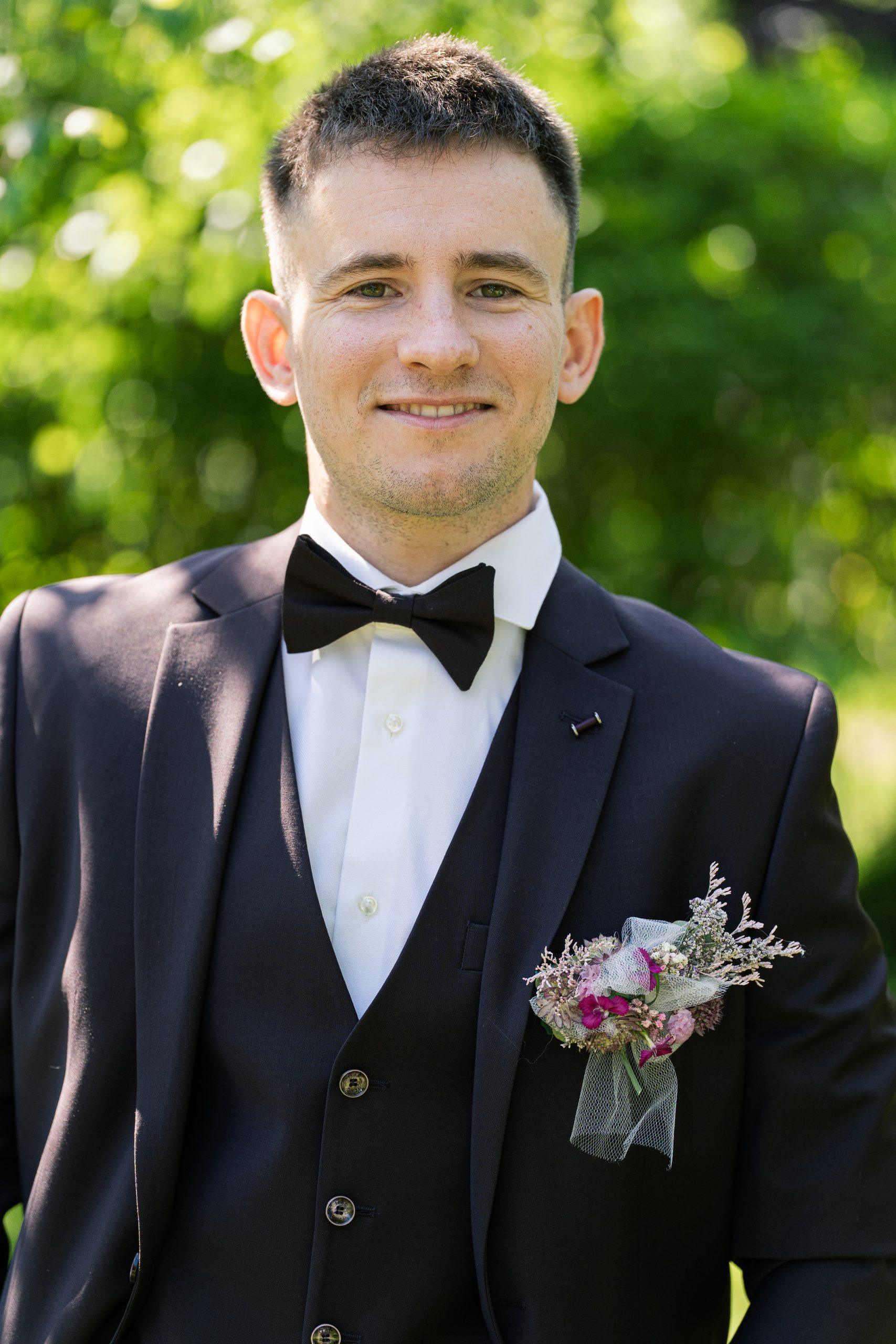 Portrait de Théo en costume noir et nœud papillon le jour de son mariage