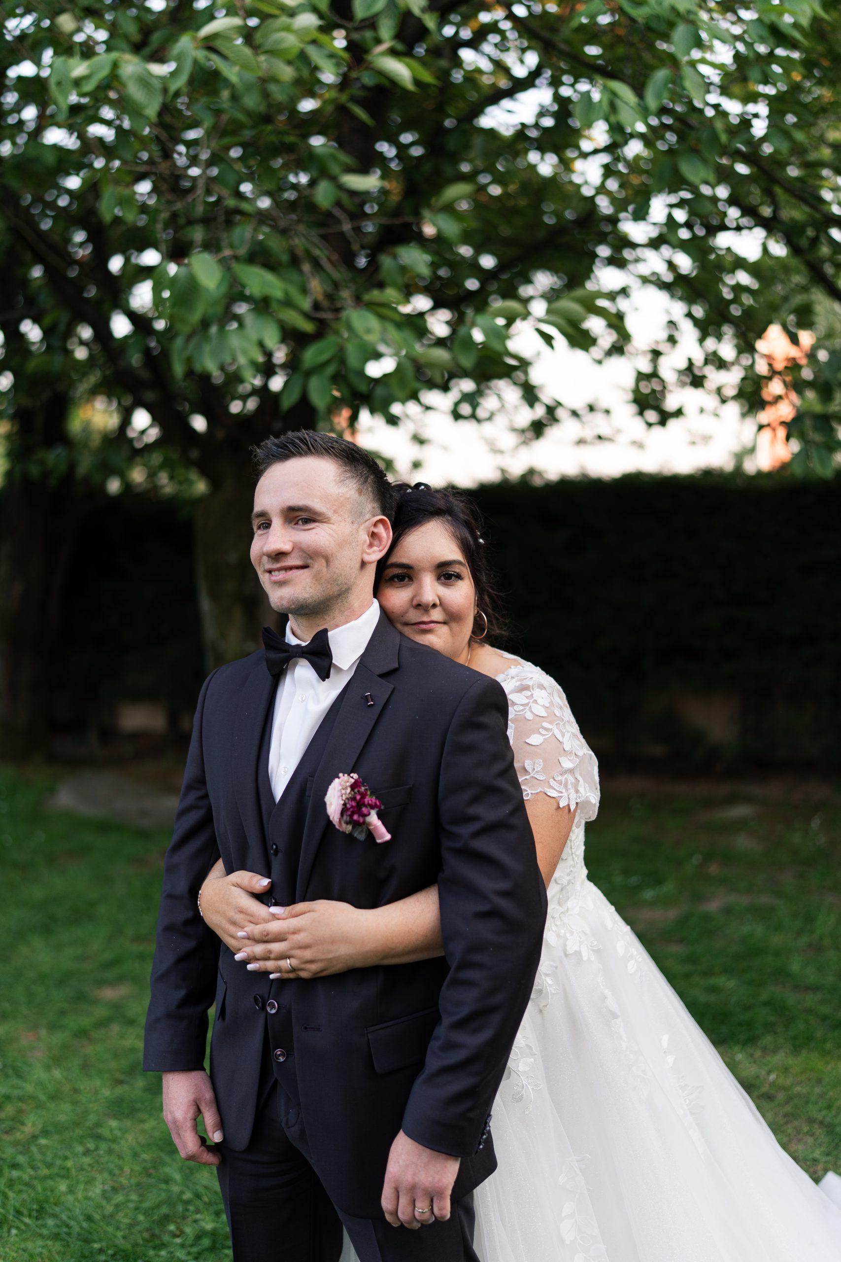 Émilie enlace Théo pendant leur séance photo de mariage en extérieur