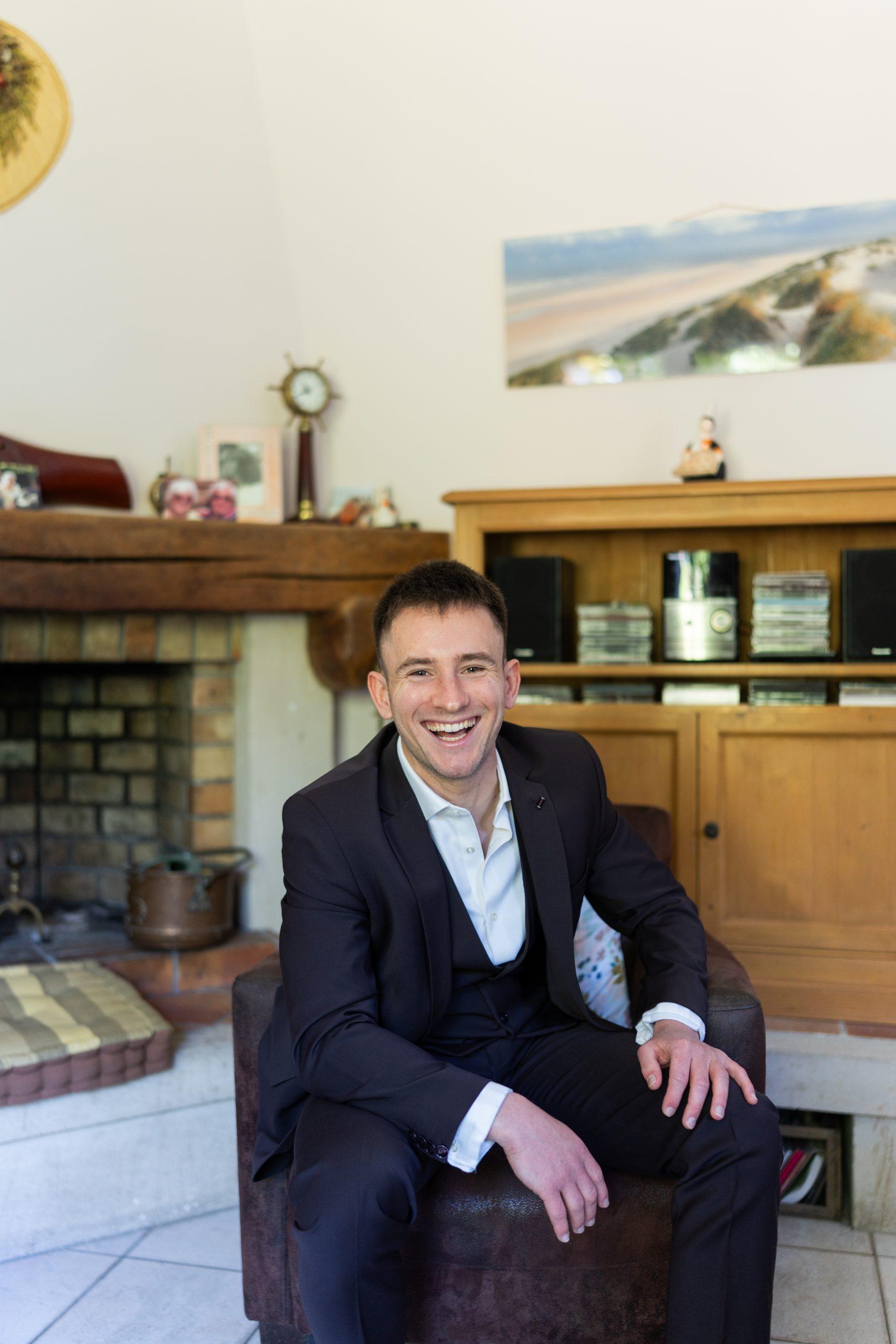 Théo souriant en costume pendant les préparatifs de son mariage, un moment authentique avec le marié